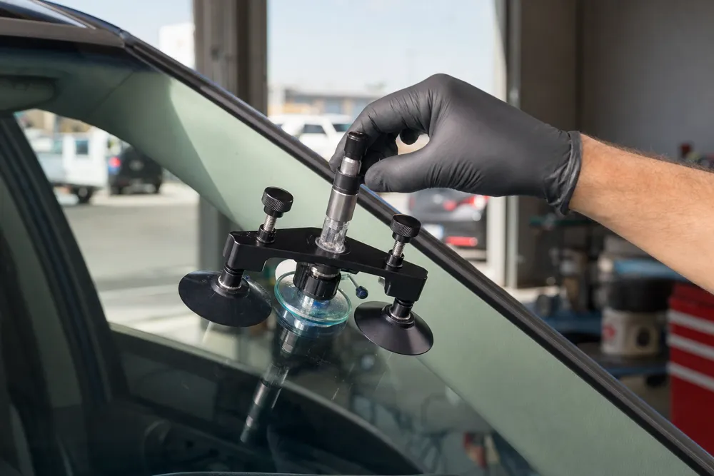 Resin injector tool clamped to a windshield during repair